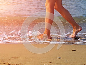 Man walking barefoot on beach by water edge
