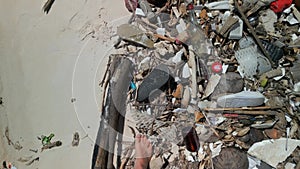 Man walking barefoot through rubbish on dirty beach with white sand