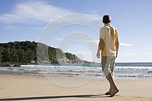 Man walking barefoot on a tropical beach