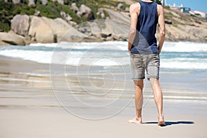 Man walking barefoot on white sand beach