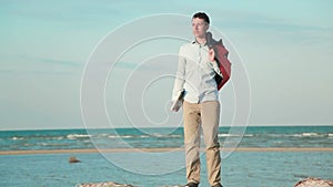 Man walking beach with laptop at hand