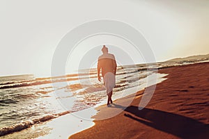 Man walking on the beach on sunset.