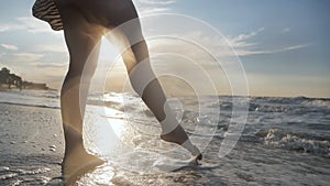 Man walking on the beach at sunset during summer vacation close up of legs and feet in sea water