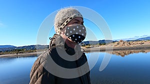 Man walking on beach in winter wearing face mask due to coronavirus