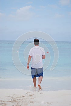 Man walking into the blue ocean
