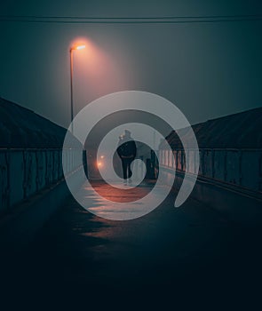 Man walking on a bridge on a foggy night