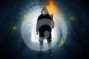 Man walking with burning flambeau in a dark tunnel