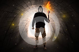 Man walking with burning flambeau in a dark tunnel