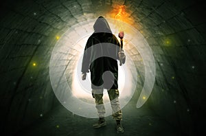 Man walking with burning flambeau in a dark tunnel