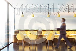 Man walking in cafe with yellow sofas