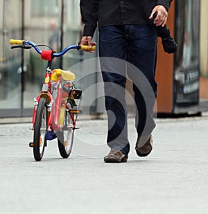 Man walking with child's bicycle