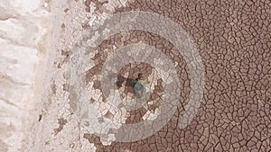 A man is walking on cracked parched lands. Aerial view