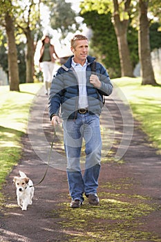 Man Walking Dog In Autumn Park