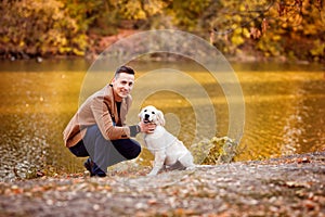 Man walking with dog in autumn Park by river.