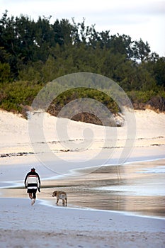 Man walking dog on beach