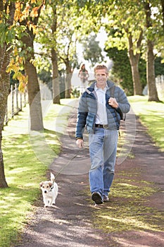 Man Walking Dog Outdoors In Autumn Park