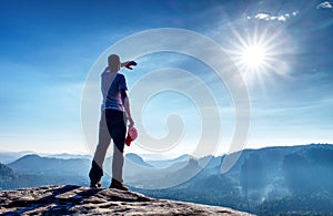 Man on edge of cliff high above misty valley. Travel hiking and Lifestyle.