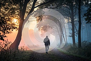 Sunrise morning man silhouette in a misty forest photo