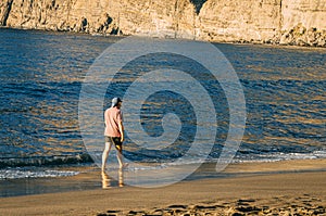 Man walking in front of the Los Gigantes cliffs in Santiago del Teide, Tenerife island. Canary Islands. Spain