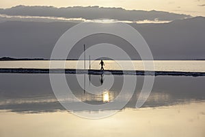 Man walking on headland at early morning under rising sun