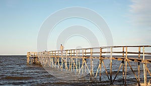 Man walking on a high wooden pier over the lake