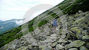 Muž kráčajúci v kopcoch na ceste s veľkou taškou v tatrách