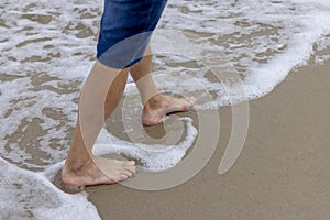 A man walking with his bare feet on the sand at the seaside of the Baltic Sea, Miedzyzdroje, Wolin Island, Poland