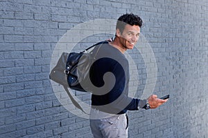 Man walking with mobile phone and bag turning and smiling