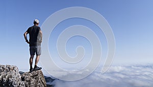 Man walking on the mountain looking at the clouds with the sky in the background