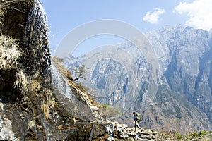 Man Walking by Mountainside Waterfall