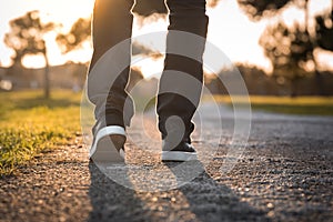 Man walking outdoors in the park at sunset. Closeup on shoe, taking a step.