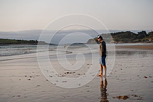 Man walking pet dog german shepherd on the beach at sunset