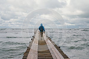 Man walking on pier on the background of stormy sea