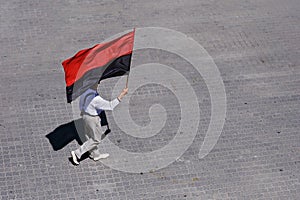 Man walking with red and black flag in hand