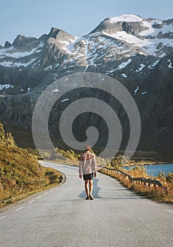 Man walking on the road enjoying mountains view solo travel vacations hitchhiking in Norway