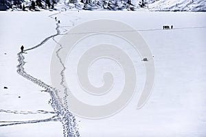 A man walking a road in the snow in the mountains. Winter mountain landscape