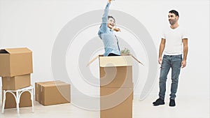 Man is walking into a room. He is seeking for his wife. Suddenly, she jumps out the boxes. They are happy and hugging