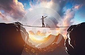 Man walking on rope between two high mountains