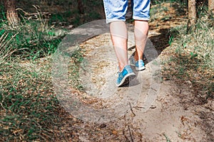 Man walking or running on path in forest summer natureo outdoors, sport shoes and exercising on fotpath.Close-up