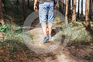 Man walking or running on path in forest summer natureo outdoors, sport shoes and exercising on fotpath.Close-up