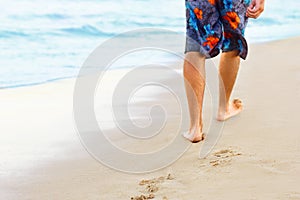 Man walking on sand beach leaving footprints in the sand. Ð¡lose up of man leg on the beach.