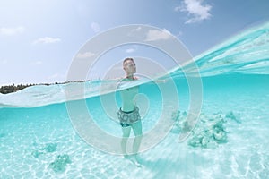 Man walking on sand seabed of turquoise sea