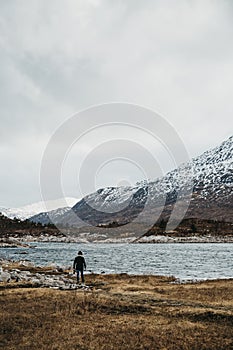 Man walking by scowcapped mountains and Loch Duich in Scottish Highlinds, Scotland