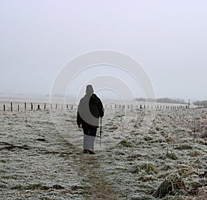 Man walking on sea wall with hoarfrost on grass