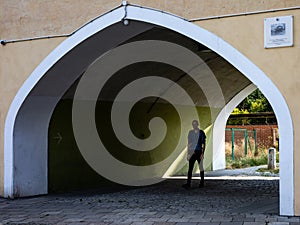 A man walking through the shadowy archway in a historical building. Karlowice district, WrocÃâaw, Poland. photo
