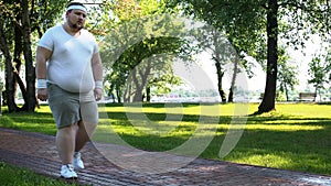 Man walking slowly, exhausted after running, cardio training for weight loss
