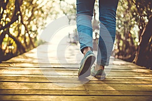 Man is walking on small wood bridge to nature walk way