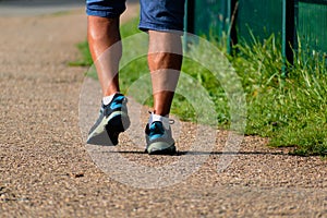 Man walking with sneakers on a path, close-up of his legs, sports activity, healthy lifetsyle