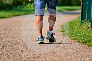 Man walking with sneakers on a path, close-up of his legs, sports activity, healthy lifetsyle