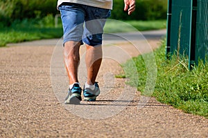 Man walking with sneakers on a path, close-up of his legs, sports activity, healthy lifetsyle